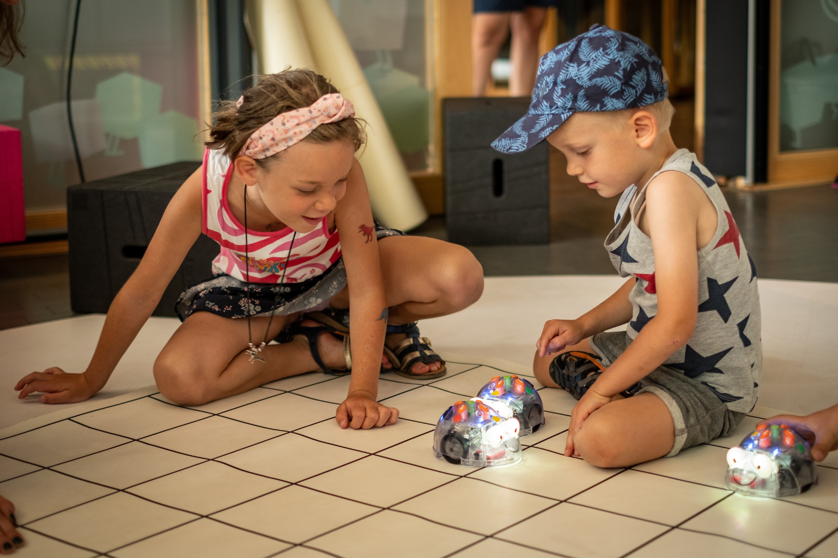 Zwei Kinder spielen mit zwei leuchtenden Robotern