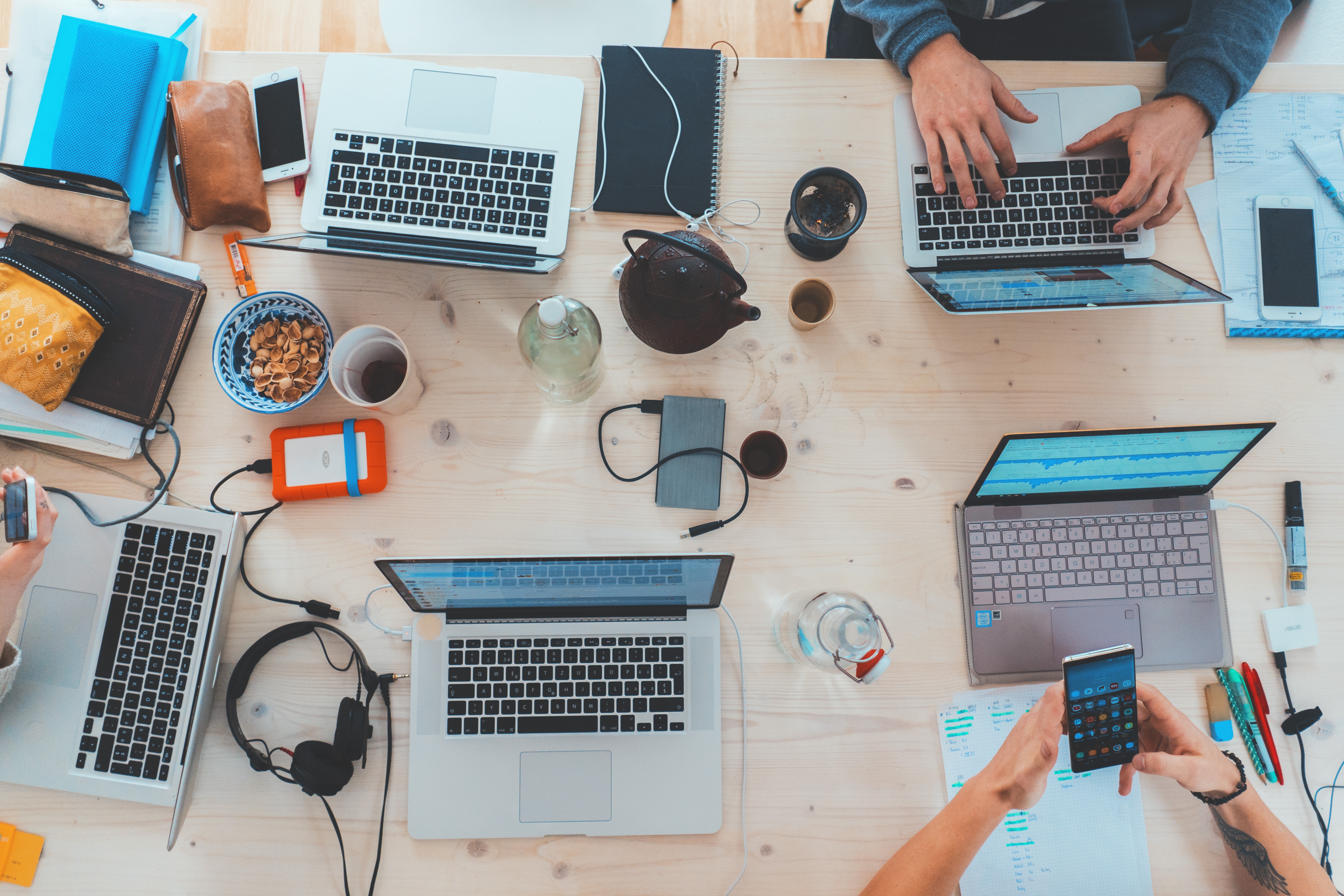 Zwei Menschen arbeiten an einem Tisch mit mehreren Laptops vor sich liegen