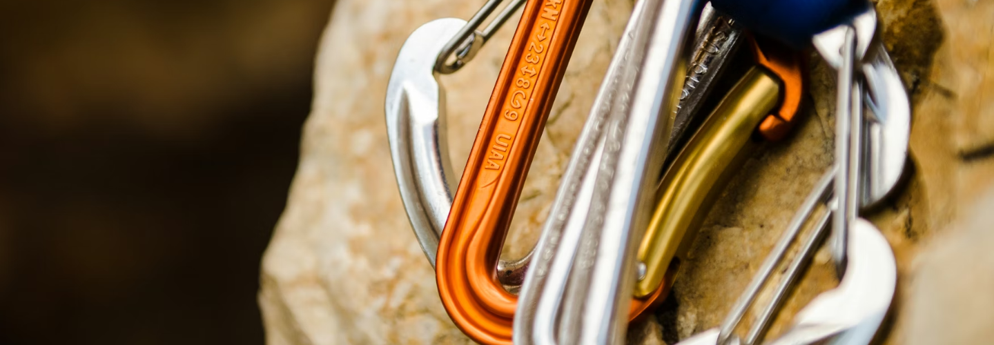 Foto mehrerer Karabinerhaken vor einer Felswand.